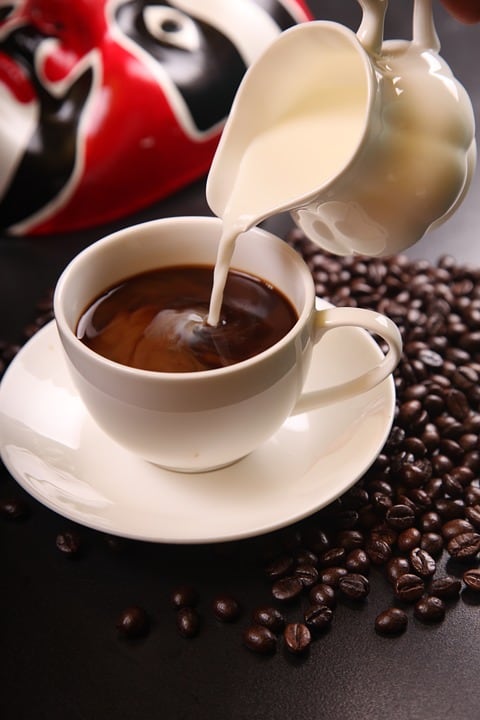 a cup of coffee in a plate with coffee beans